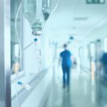 Silhouette of a doctor walking quickly in a hospital corridor.