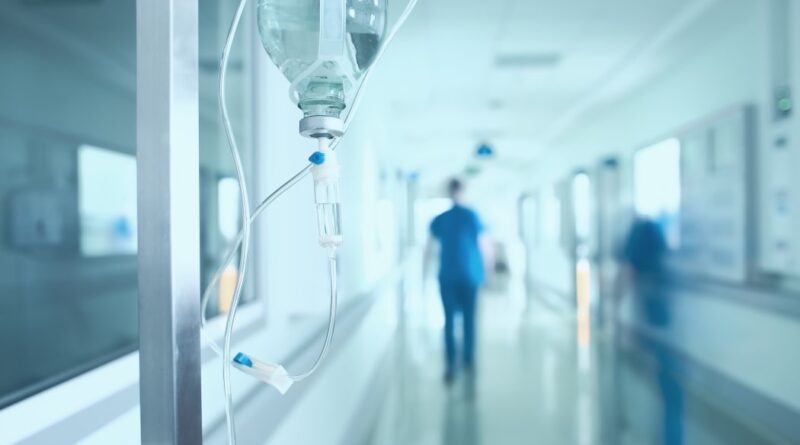 Silhouette of a doctor walking quickly in a hospital corridor.