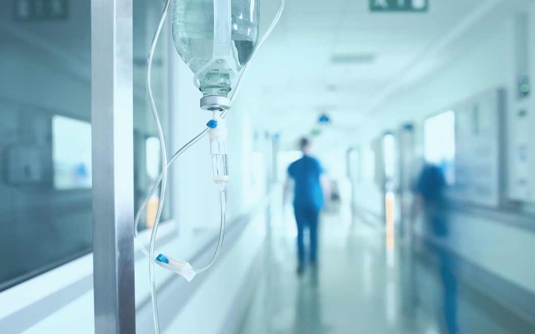 Silhouette of a doctor walking quickly in a hospital corridor.